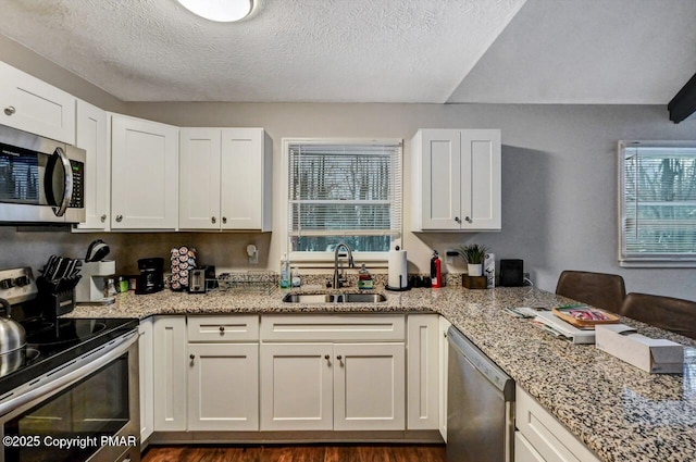 kitchen featuring sink, a textured ceiling, appliances with stainless steel finishes, light stone countertops, and white cabinets