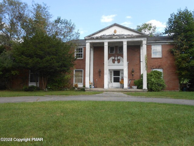 neoclassical home with brick siding and a front lawn