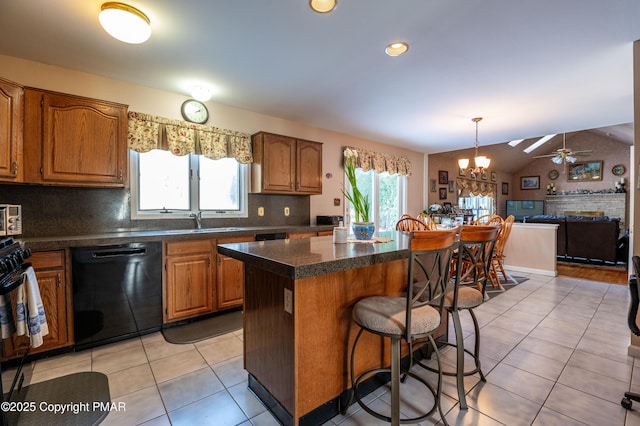 kitchen with light tile patterned floors, a kitchen bar, a kitchen island, plenty of natural light, and dishwasher