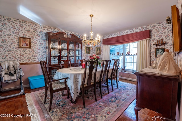 dining space featuring a wainscoted wall, a notable chandelier, baseboards, and wallpapered walls