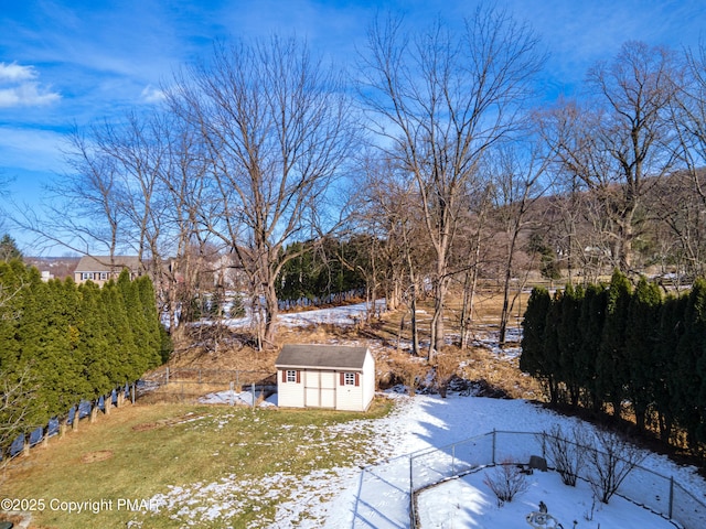 yard layered in snow featuring an outbuilding, fence, and a storage unit