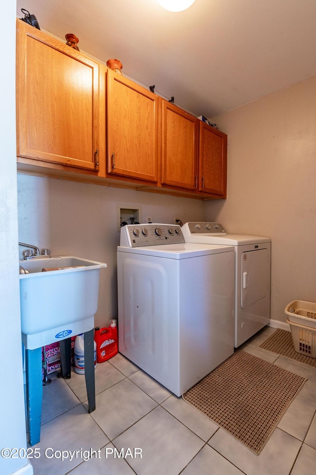 laundry room featuring washer and clothes dryer, light tile patterned flooring, and cabinet space