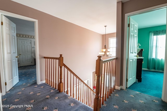 corridor featuring an inviting chandelier, carpet, an upstairs landing, and a healthy amount of sunlight