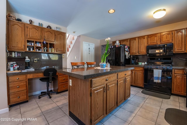 kitchen featuring light tile patterned floors, a kitchen island, brown cabinets, black appliances, and dark countertops