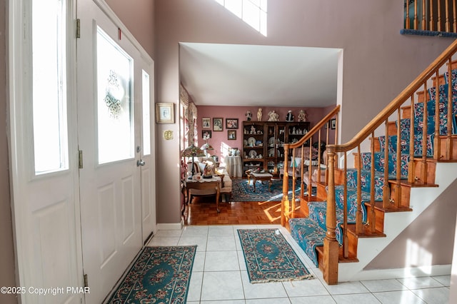 tiled foyer entrance with stairway and baseboards