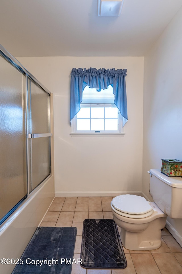 bathroom featuring bath / shower combo with glass door, tile patterned flooring, toilet, and baseboards