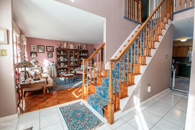 stairs with tile patterned flooring, a high ceiling, and baseboards