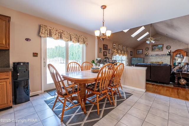 dining room with light tile patterned floors, baseboards, lofted ceiling with skylight, and an inviting chandelier