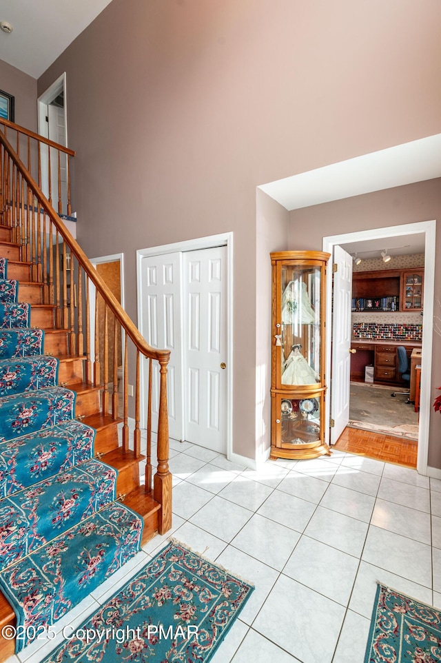 entrance foyer with tile patterned flooring, stairway, and a high ceiling