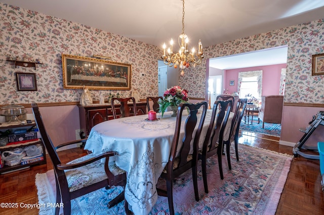 dining area featuring a chandelier, a wainscoted wall, and wallpapered walls