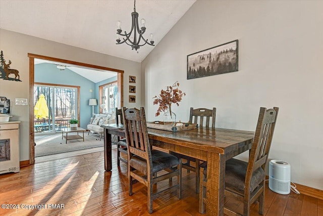 dining room with lofted ceiling, hardwood / wood-style flooring, and an inviting chandelier