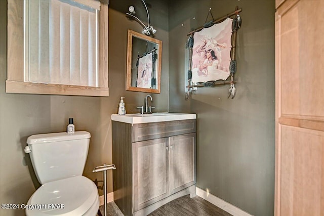 bathroom featuring baseboards, vanity, toilet, and wood finished floors