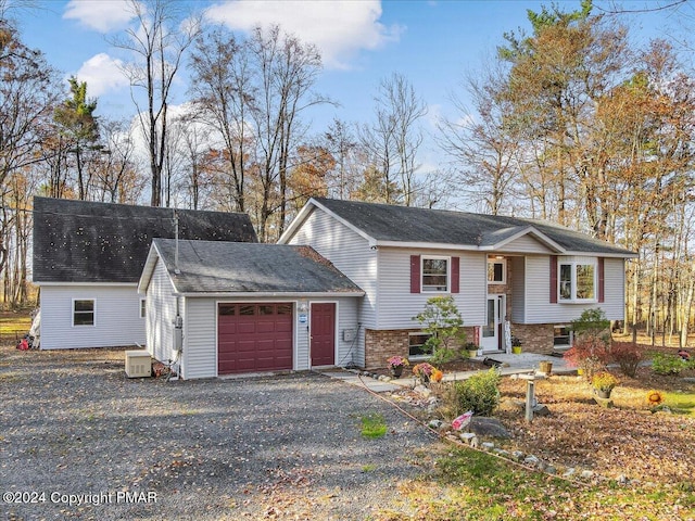 split foyer home featuring a garage and aphalt driveway