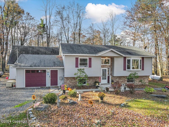 split foyer home featuring an attached garage, driveway, and brick siding