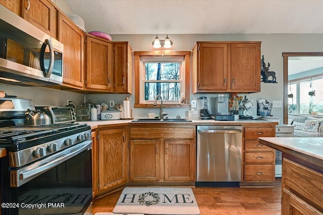 kitchen with a wealth of natural light, appliances with stainless steel finishes, light countertops, and a sink