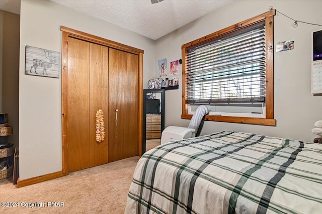 bedroom featuring a textured ceiling, a closet, and light colored carpet