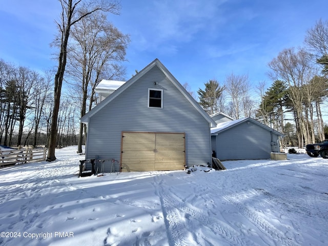 snow covered property with a garage and an outbuilding