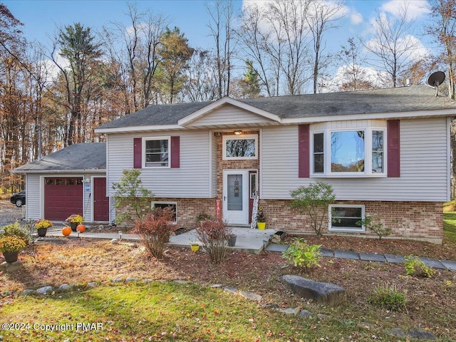 raised ranch with an attached garage and brick siding