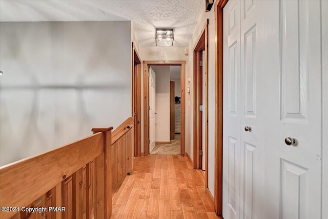 hall featuring light wood-style flooring and a textured ceiling