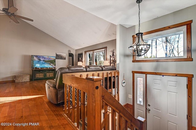 foyer entrance with dark wood-type flooring, a notable chandelier, and vaulted ceiling