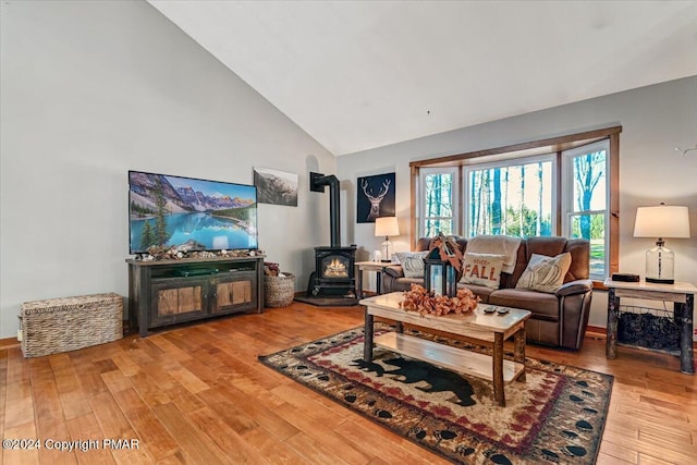 living area featuring a wood stove, high vaulted ceiling, and hardwood / wood-style floors