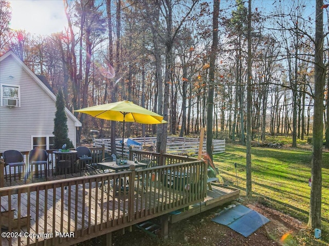 deck featuring outdoor dining area and a lawn