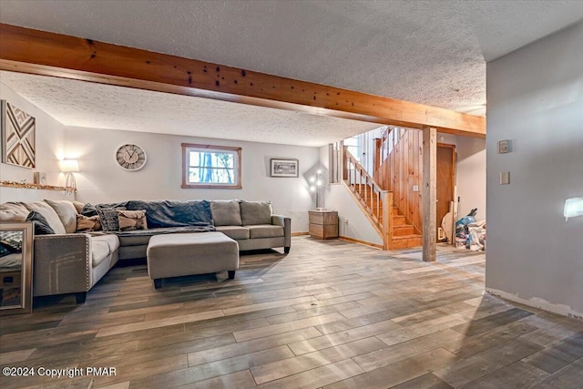 living room featuring a textured ceiling, stairway, beamed ceiling, and wood finished floors