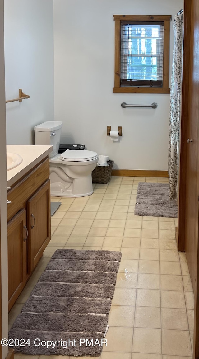 bathroom with a shower with curtain, toilet, vanity, tile patterned flooring, and baseboards