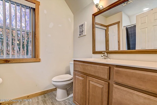 bathroom featuring toilet, a shower with shower curtain, wood finished floors, vanity, and baseboards