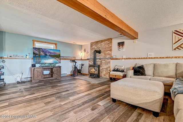 living area with beamed ceiling, baseboard heating, wood finished floors, and a wood stove