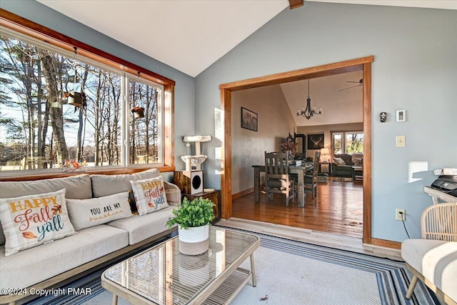 living room with a notable chandelier, vaulted ceiling, baseboards, and wood finished floors