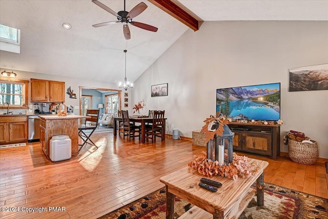 living area with beam ceiling, high vaulted ceiling, light wood-type flooring, baseboards, and ceiling fan with notable chandelier