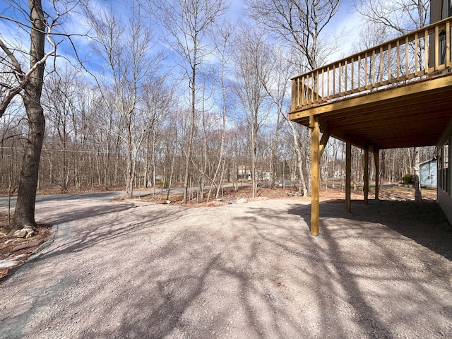 view of yard featuring a wooden deck, a carport, and aphalt driveway