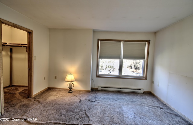 unfurnished bedroom featuring carpet floors, a baseboard radiator, a spacious closet, and baseboards