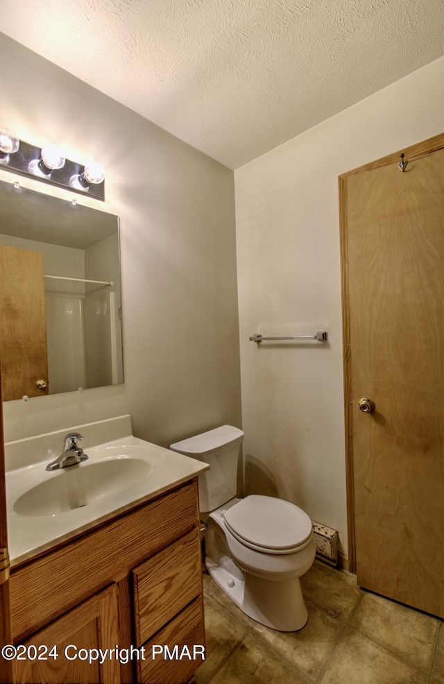 full bathroom with a textured ceiling, vanity, toilet, and tile patterned floors