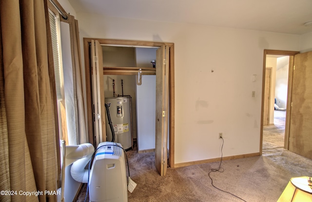 carpeted bedroom with a closet, electric water heater, and baseboards