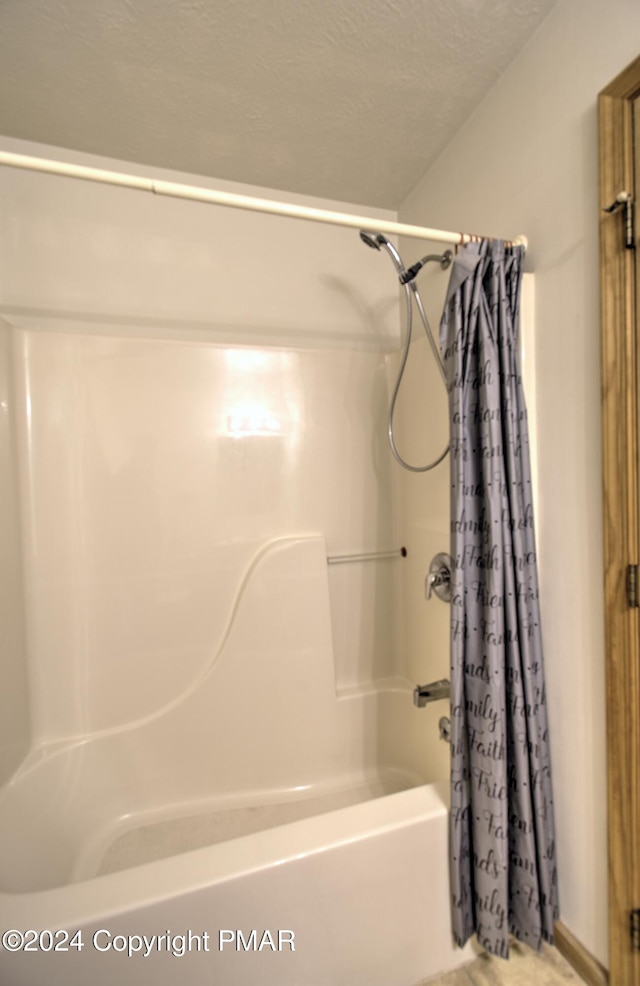 full bath with a textured ceiling and shower / tub combo with curtain