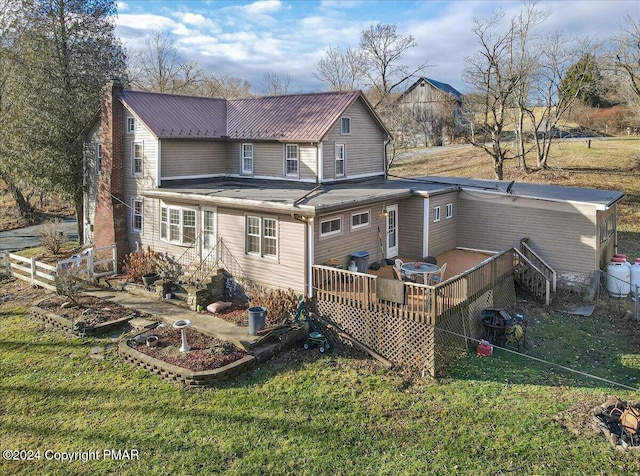 rear view of house featuring a chimney, a lawn, and a wooden deck