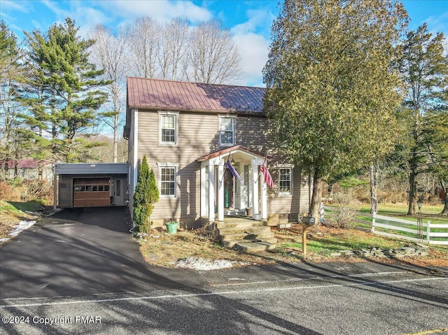 view of front facade featuring an attached garage, driveway, and metal roof