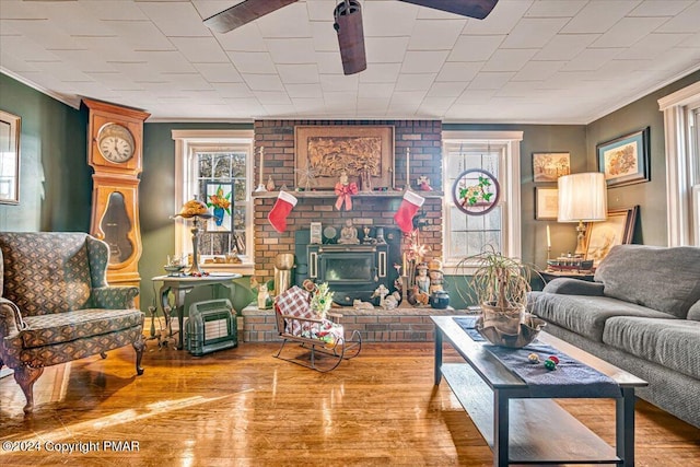 living room with a wood stove, ornamental molding, and wood finished floors