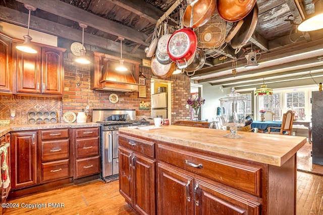 kitchen featuring stainless steel appliances, beamed ceiling, wooden counters, and custom range hood