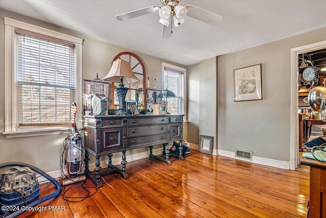 interior space with baseboards, visible vents, ceiling fan, and hardwood / wood-style floors