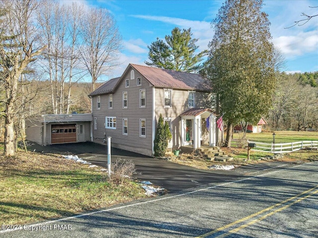 view of side of home featuring aphalt driveway, metal roof, and fence