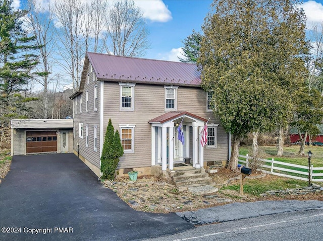 view of front facade with a garage, metal roof, fence, and driveway