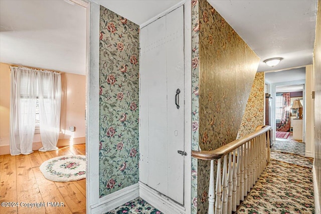 corridor with wood-type flooring, baseboards, and wallpapered walls