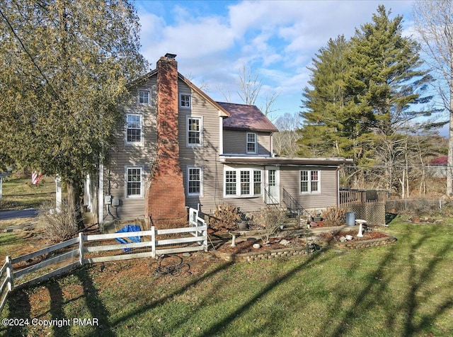 rear view of house with fence, a chimney, and a lawn