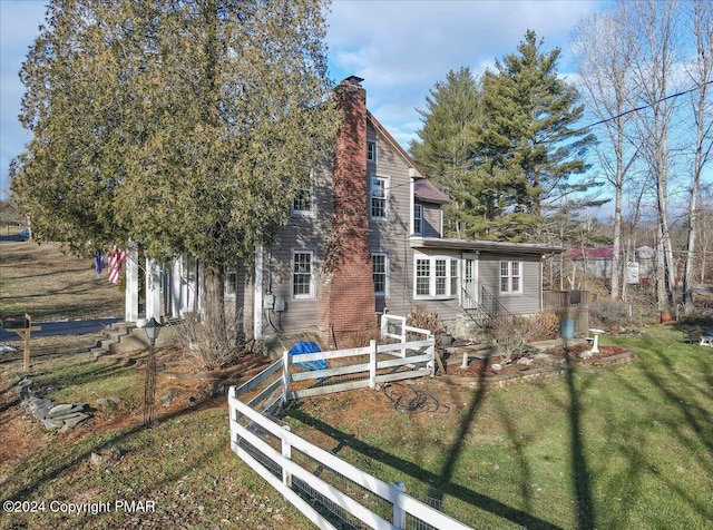 view of side of property featuring a yard, fence, and a chimney