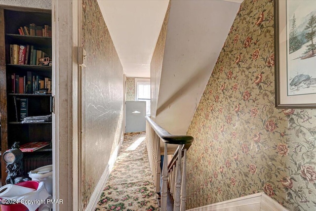 hall with carpet floors, wallpapered walls, and an upstairs landing