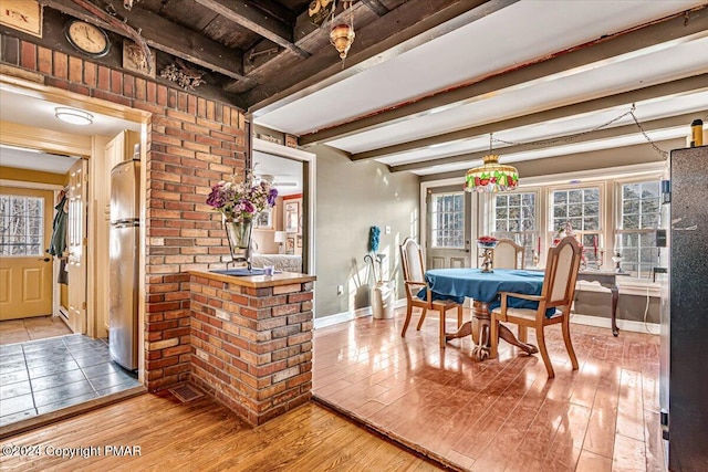 dining area with wood-type flooring, baseboards, and beamed ceiling