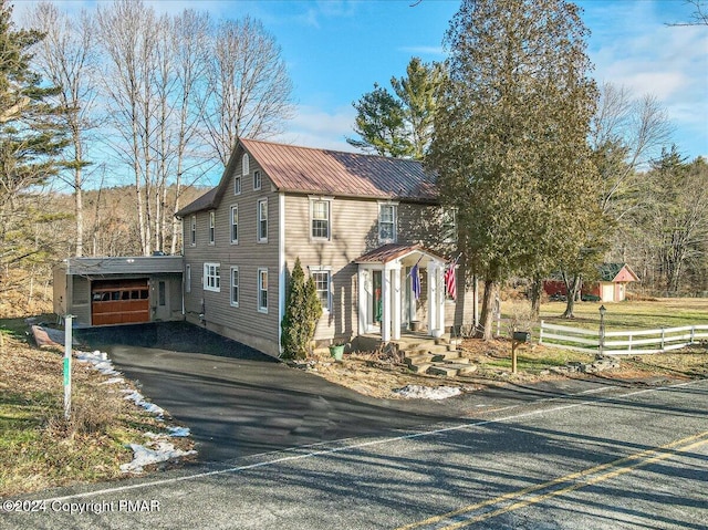 view of front of property with metal roof, fence, driveway, and an attached garage